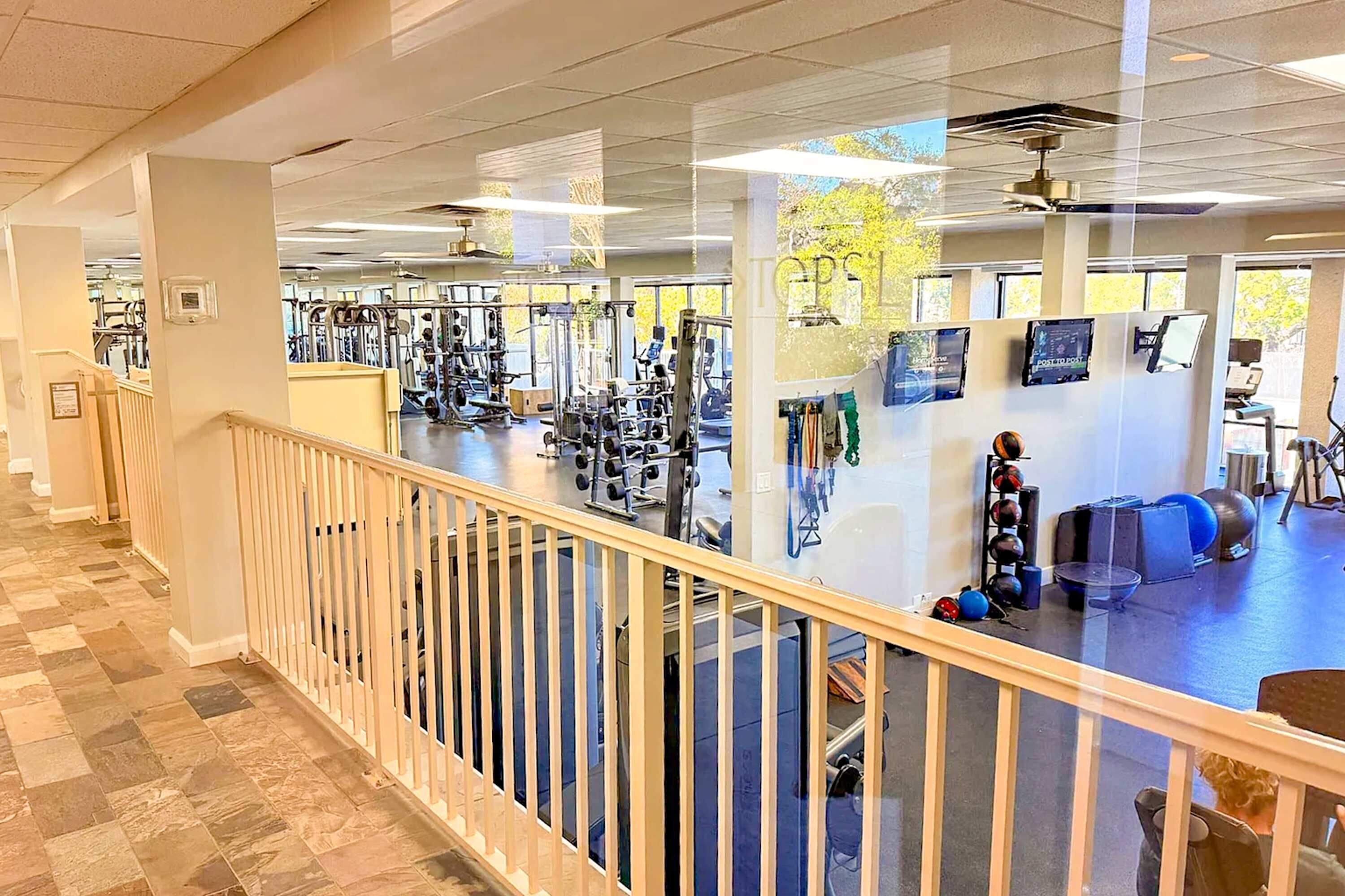 A gym with exercise equipment, a staircase, and a railing.