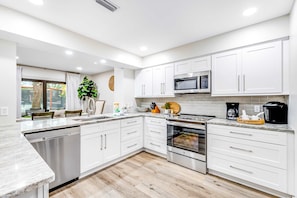 A modern kitchen with white cabinets, a dishwasher, an oven, and a microwave. - Exclusive 2BR condo, steps to beach & pool (Miramar Beach)