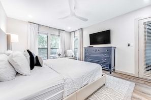A bedroom with a bed, a dresser, a television, and a window with curtains. - Exclusive 2BR condo, steps to beach & pool (Miramar Beach)