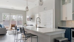 A modern kitchen with a large island, bar stools, and a dining area with a sofa and chairs. - Landing | Stylish 2BD, Clubhouse, Gym (Decatur)