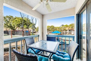 A covered patio with a glass table and wicker chairs, overlooking a residential area. - Beach access + resort amenities at TOPS'L (Miramar Beach)