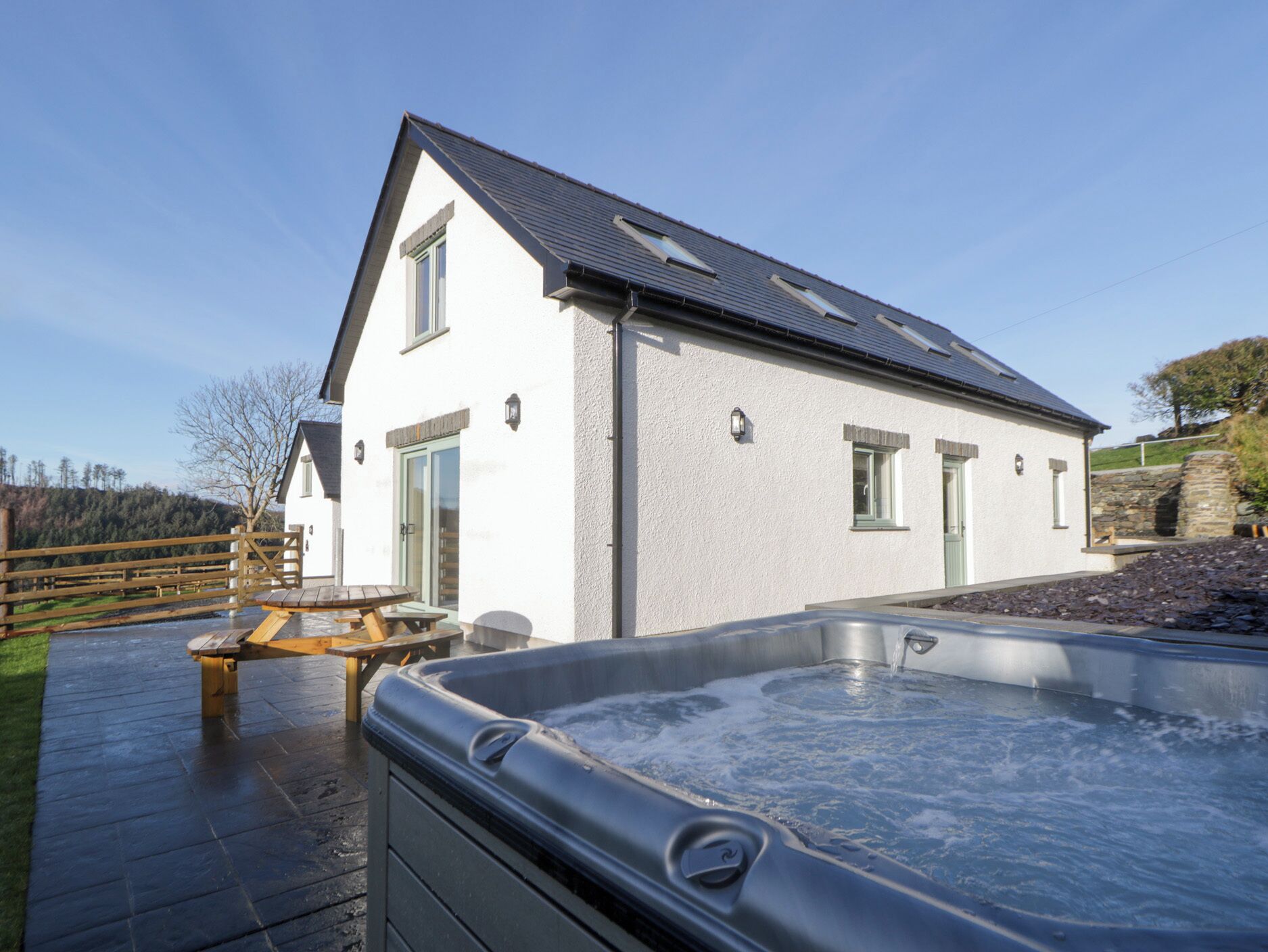 Een modern huis met een hottub en een houten terras.