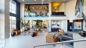 A spacious lobby with a high ceiling, multiple seating areas, and a staircase leading to an upper level. - Landing | Chic 2BD, Gym, Courtyard (Decatur)