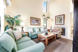 A living room with a sofa, armchair, coffee table, and a fireplace. - 2BR villa: steps to beach & tennis courts (Miramar Beach)
