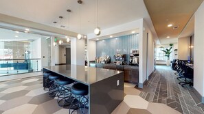 A modern kitchen area with a bar counter, seating, and a patterned backsplash. - Landing | Stylish 1BD, Gym, Courtyard (Decatur)