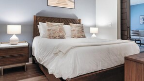 A neatly arranged bedroom with a large bed, two bedside tables, and a view of a balcony. - Landing | Stylish 1BD, Gym, Courtyard (Decatur)