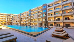 Et hotel med flere etager og en central swimmingpool omgivet af liggestole og solstole.