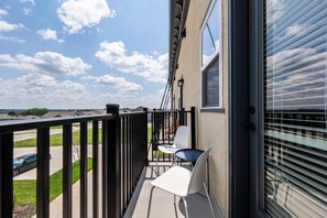 A balcony with a view of the sky and a parking lot.