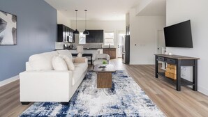 A modern living room with a sofa, coffee table, and TV stand. - Landing | Spectacular 3BD in Lee's Summit (Lee's Summit)