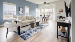 A modern living room with a sofa, coffee table, and dining area. - Landing | Incredible 3BD in Lee's Summit (Lee's Summit)
