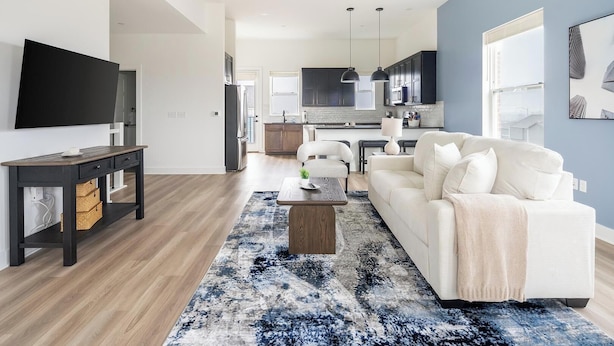 A modern living room with a sofa, a coffee table, and a TV. - Landing | Incredible 3BD in Lee's Summit (Lee's Summit)