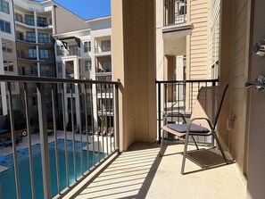 A balcony with a pool, chairs, and a view of other buildings.