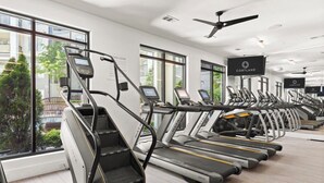 Une salle de sport moderne équipée de tapis de course, de vélos d’appartement et d’une grande fenêtre donnant sur l’extérieur.