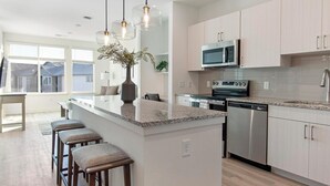 Uma cozinha moderna com ilha central, eletrodomésticos de aço inoxidável e uma grande janela.