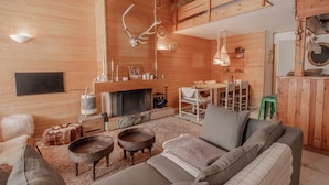 Un interior de madera acogedor, con chimenea, zona de estar y decoración rústica.
