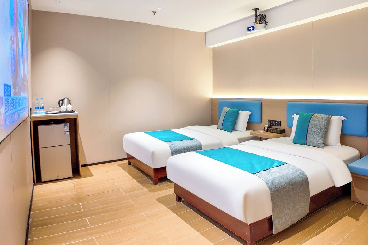 A hotel room with two beds, a small desk, and a seating area.