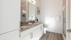 A modern bathroom with a granite countertop, a large mirror, a toilet, and a shower area. - Landing | Amazing 2BD, Clubhouse, Gym (Longmont)