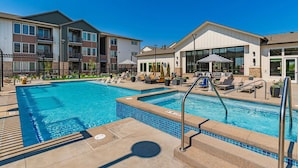 A swimming pool with lounge chairs and umbrellas, surrounded by apartment buildings. - Landing | Chic 2BD, Clubhouse, Gym (Longmont)