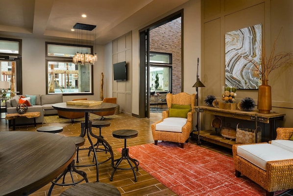 A modern living room with a sofa, armchairs, a coffee table, a dining table, and a fireplace.