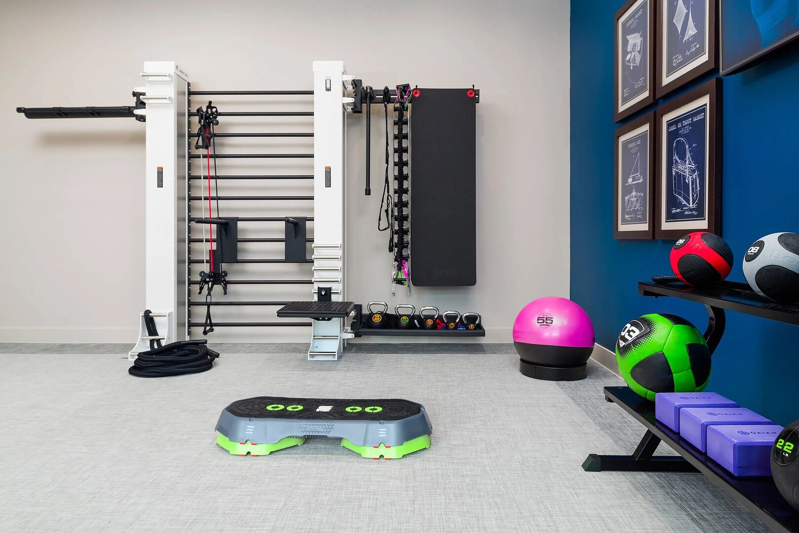 A gym with a pull-up bar, weight plates, kettlebells, and a step platform.