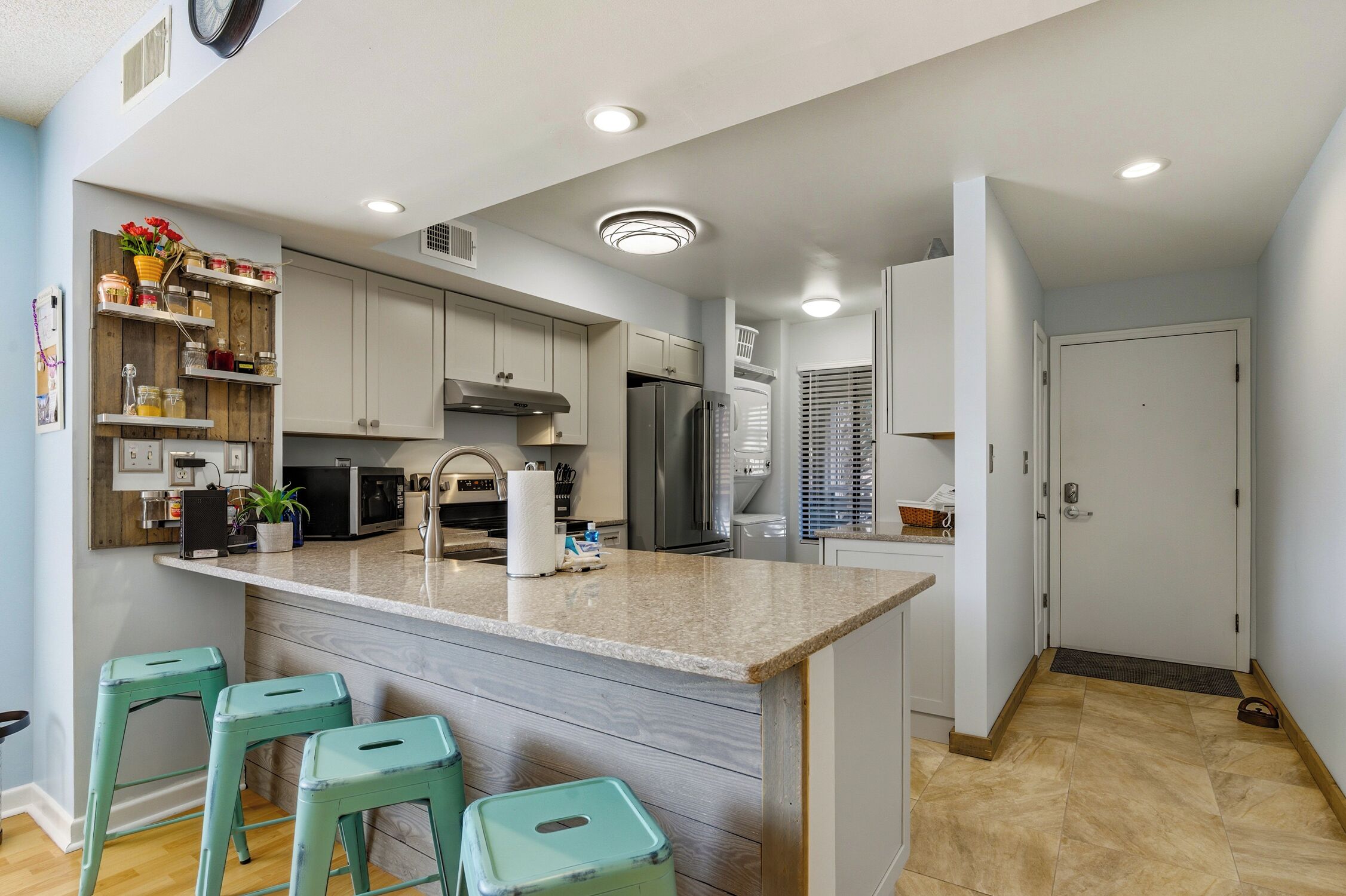 A modern kitchen with a central island, bar stools, and built-in appliances.
