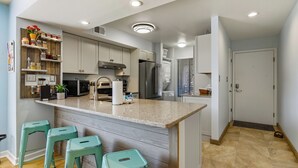 A modern kitchen with a central island, bar stools, and built-in appliances. - ☀️Great Location | Walk to Beach | Heron Pointe B-8☀️ (Myrtle Beach)
