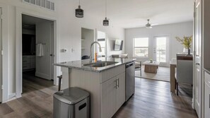 Una cocina moderna con una isla central, electrodomésticos de acero inoxidable y vistas al área de estar.