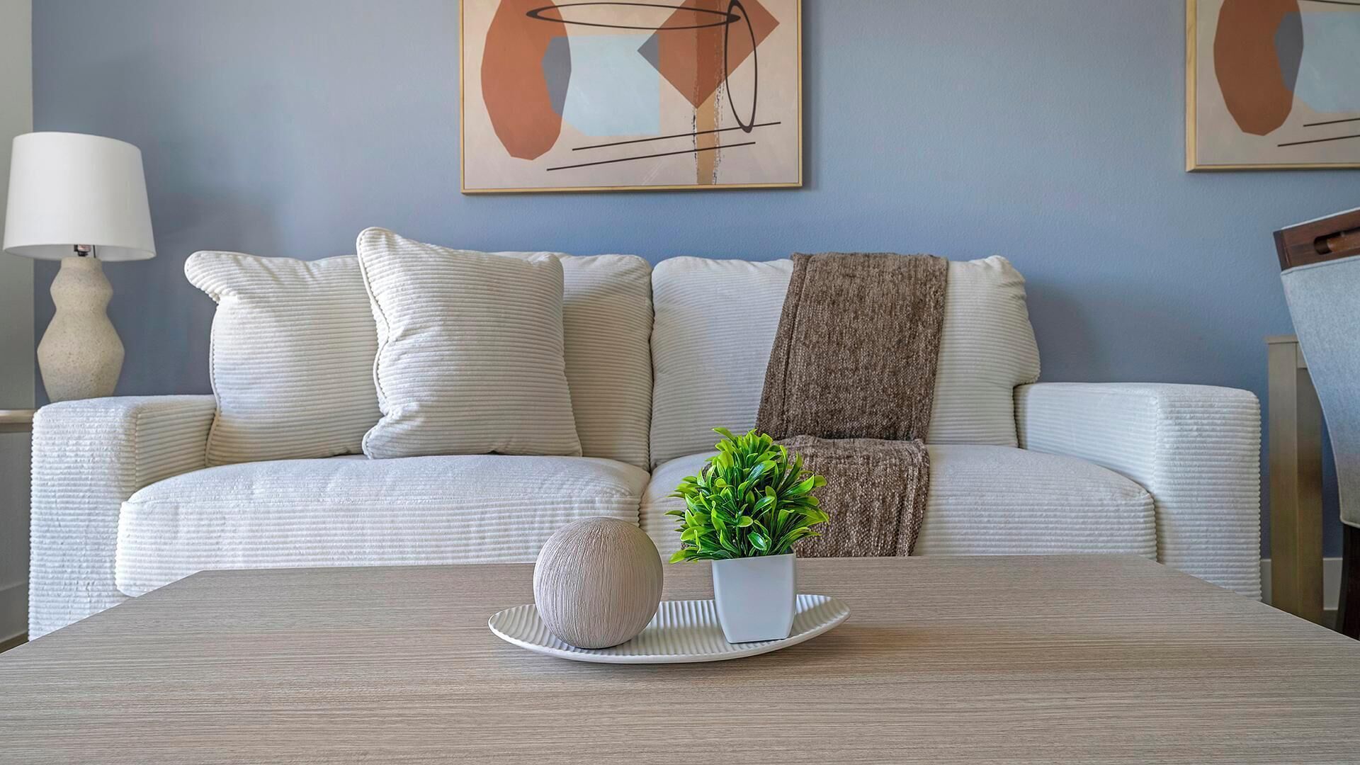 Una sala de estar moderna con un sofá, una mesa de centro y una lámpara.