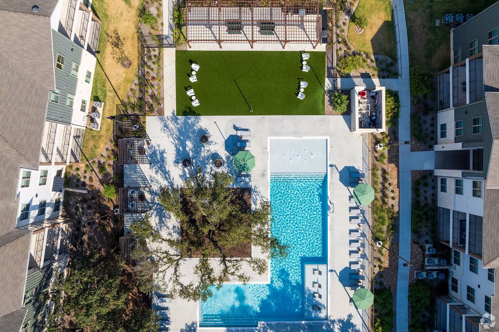 Luchtbeeld van een woonwijk met een zwembad, een tennisbaan en aangrenzende appartementencomplexen.