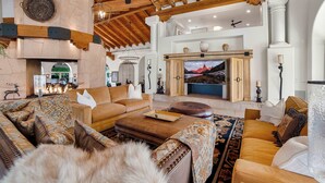 Una sala de estar amplia con chimenea, asientos cómodos y una gran pantalla de televisión.