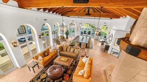 Amplia sala de estar con un sofá grande, una mesa de centro y una chimenea. Hay varias opciones de asiento y una mesa de comedor al fondo.
