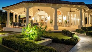 Un patio techado al aire libre con asientos, columnas y un ventilador de techo.