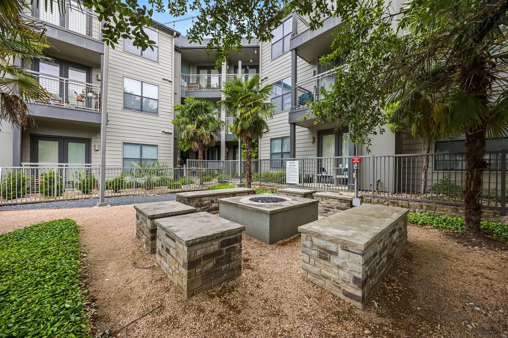 A modern apartment building with a courtyard featuring a fire pit and seating area.