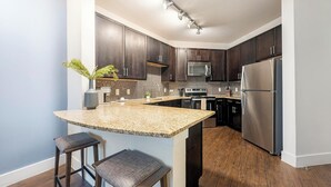Una cucina moderna con mobili in legno scuro, elettrodomestici in acciaio inossidabile e un piano di lavoro in granito.