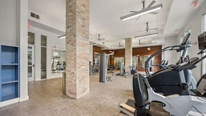 Un gimnasio con equipo de ejercicio, un pilar de ladrillo y un muro con espejos.