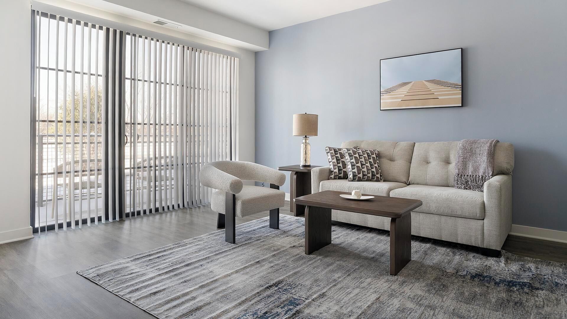 Un salon moderne avec un canapé, un fauteuil, une table basse et un tableau accroché au mur.