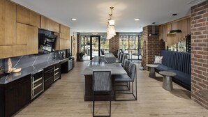 Een moderne keuken met een groot eiland, een eethoek met een lange tafel en stoelen, en een zithoek met een bank en fauteuils.