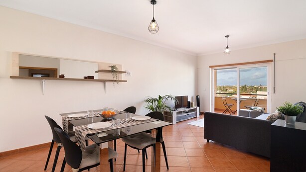 Cocina moderna con comedor, televisor y balcón con vistas.