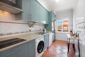 Eine Küche mit Waschmaschine, Spüle und Fenster mit Blick auf Gebäude.