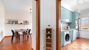 Una cocina moderna con electrodomésticos integrados, un comedor con mesa y sillas, y un área de lavandería con lavadora.