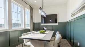 A dining area with a large table, chairs, a chandelier, and a flat-screen TV on the wall. - Landing | Incredible 2BD, Clubhouse, Pool (Port Wentworth)