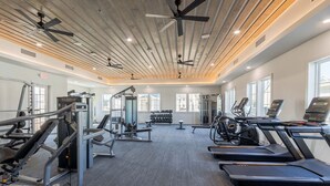 A gym with treadmills, weight machines, and a ceiling fan.