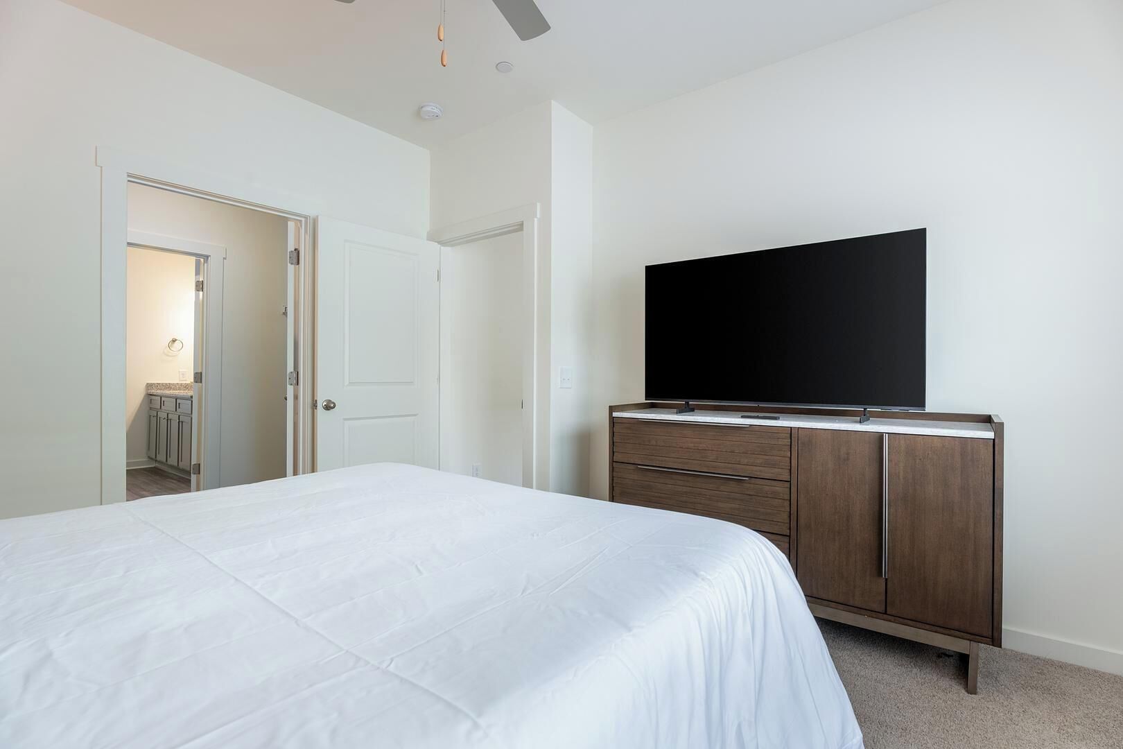 A bedroom with a bed, a dresser, and a television on the wall.