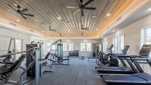 Ett gym med löpband, styrketräningsmaskiner och en takfläkt.
