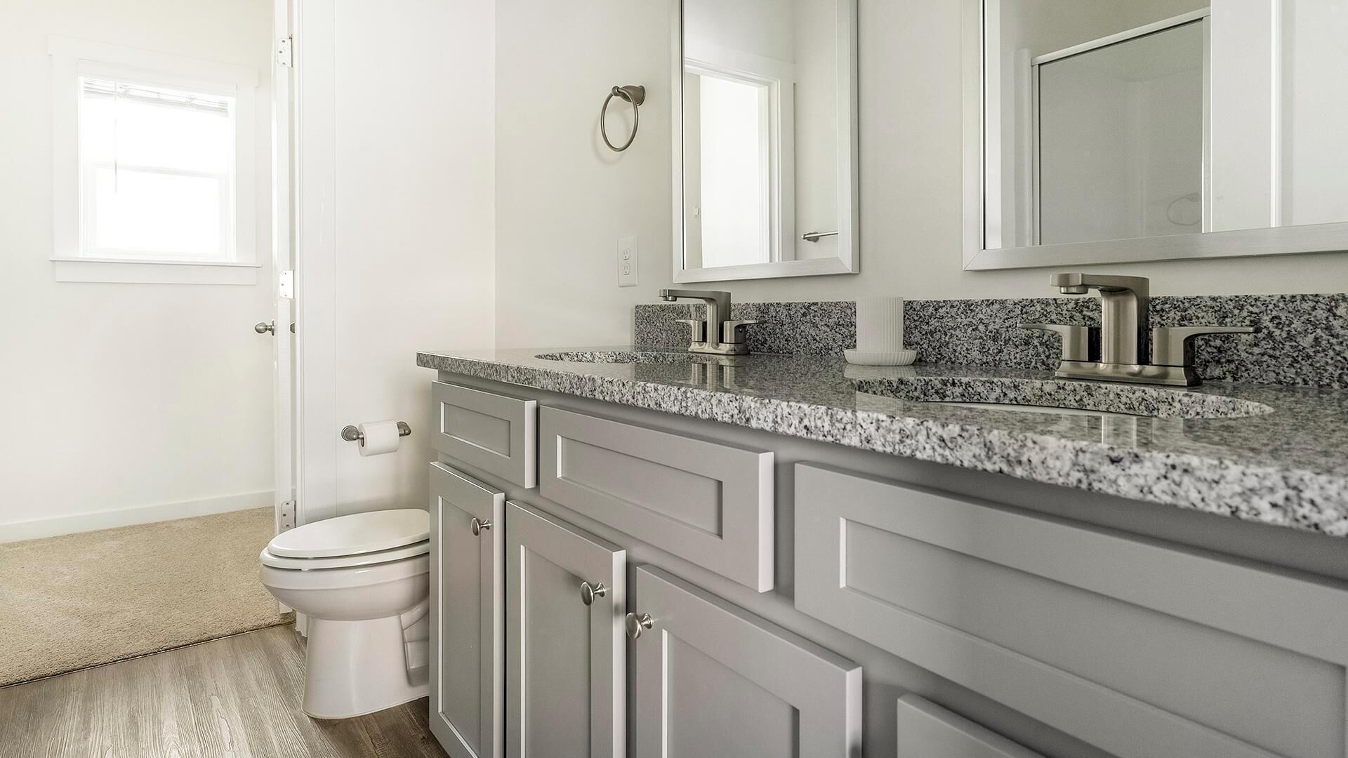 Een badkamer met toilet, wastafel met spiegel en een granieten aanrecht.