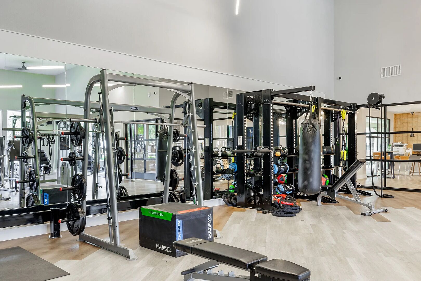 A gym with weightlifting equipment, a punching bag, and a bench.
