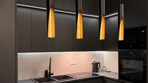 A modern kitchen with dark cabinetry, a central island, and pendant lights.