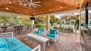 An outdoor patio with wooden ceiling, seating, and a pool area. - Landing | Beautiful 2BD, Gym, Clubhouse (Cedar Park)
