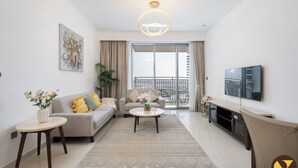 Een moderne woonkamer met een bank, salontafel en televisie. Er is een balkon met uitzicht.