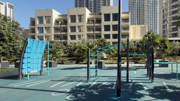 A playground with exercise equipment, surrounded by residential buildings and greenery.